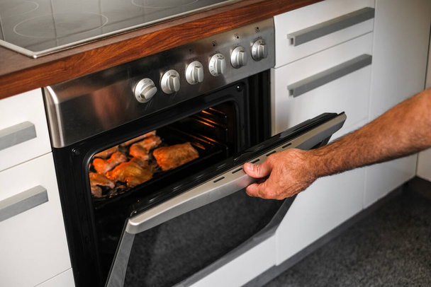 mannelijke kok bakken vlees in de oven - Foto, afbeelding