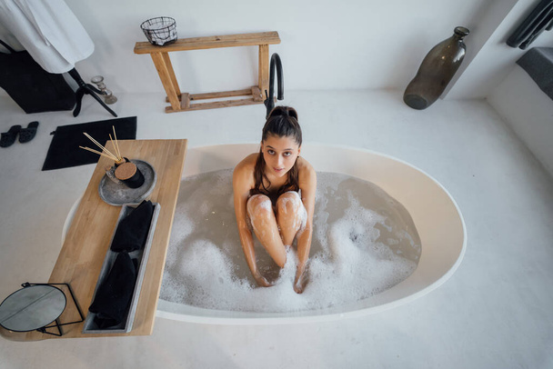 Mooie jonge vrouw die thuis in bad gaat - Foto, afbeelding