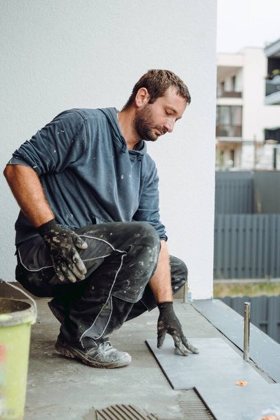 industrial worker, handyman installing ceramic tiles on balcony floor. Balcony area covered in ceramic tiles with strong adhesive - Valokuva, kuva