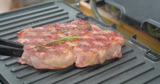 Delicious juicy beef steak with rosemary is cooked on an electric grill. Aged prime rare roast grilling tenderloin fresh marble tenderness beef. Prime beef fry on electric roaster. - Filmati, video