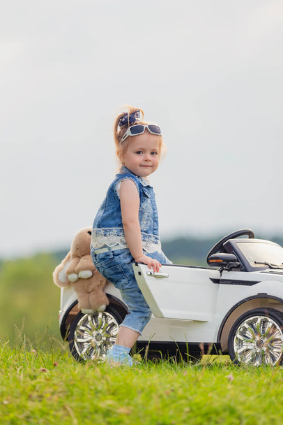 small child stands near his car on the lawn - Foto, imagen