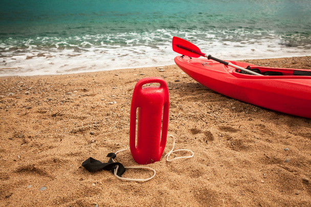 рятувальний буй і рятувальний каяк на піщаному пляжі
 - Фото, зображення