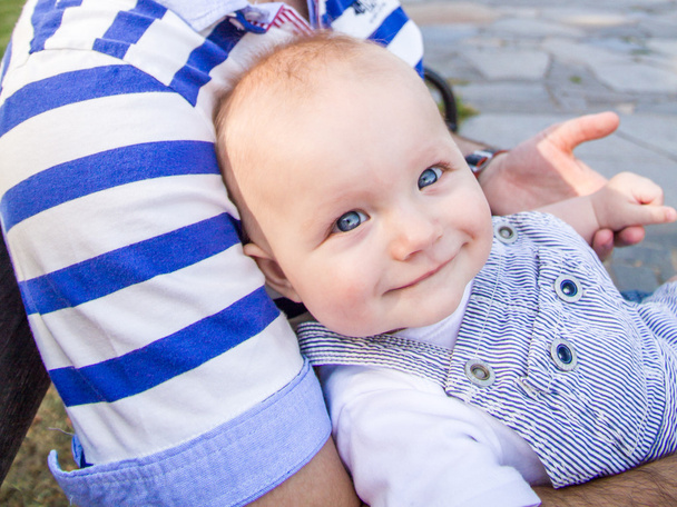 Erkek bebek yaz saati bir parkta babasının elini tutarak gülümsüyor - Fotoğraf, Görsel