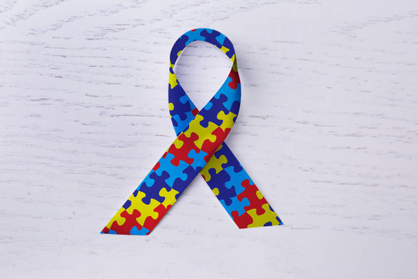 World Autism Awareness Day. Colorful puzzle ribbon on white wooden background, top view - Zdjęcie, obraz
