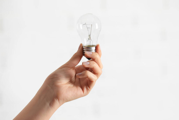 Woman holding light bulb on white background, closeup. Space for text - Φωτογραφία, εικόνα