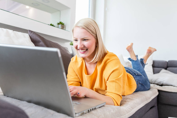 幸せな女の子のラップトップでオンライン チャットします。コンピューター上の友人とメッセージング笑顔の金髪女性。ソーシャル メディア、通信、技術コンセプトをコピー スペースの壁に - 写真・画像