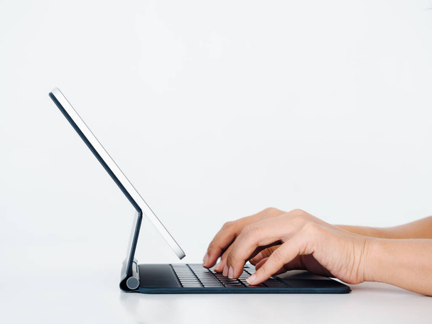 Tippen der Hände auf dem Tastaturcomputer auf dem digitalen Tablet-Bildschirm isoliert auf weißem Hintergrund mit Kopierraum. Geschäfts- und Technologiekonzept, Seitenansicht. - Foto, Bild