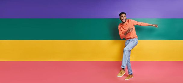 Full length of happy African man dancing against colorful background - Foto, imagen