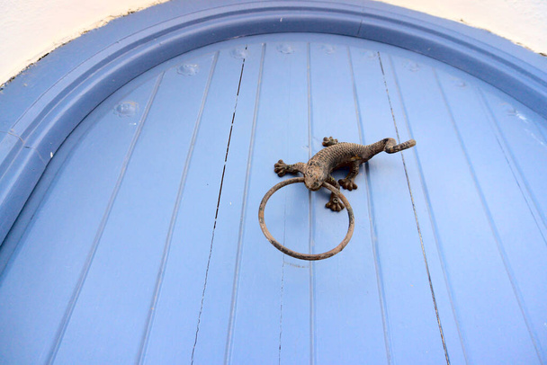 Niebieskie drewniane drzwi mają pukanie do drzwi w kształcie jaszczurki. Piękne wejście do domu, vintage dekoracji. Wysokiej jakości zdjęcie - Zdjęcie, obraz