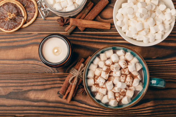 Cup of tasty cocoa drink and marshmallows in blue cup.Spices and marshmallows for winter drinks on brown texture table.Winter hot drink.Hot chocolate with marshmallow and spices.Copy space. - Foto, Bild