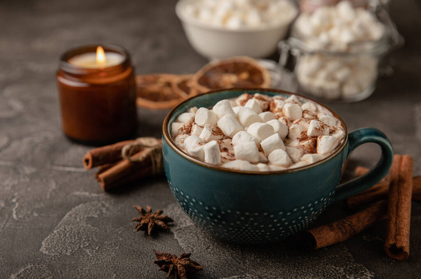 Cup of tasty cocoa drink and marshmallows in blue cup.Spices and marshmallows for winter drinks on black texture table.Winter hot drink.Hot chocolate with marshmallow and spices.Copy space. - Zdjęcie, obraz