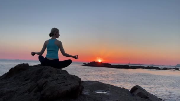 Mujer de yoga en posición de loto en la costa del océano al atardecer increíble. - Imágenes, Vídeo