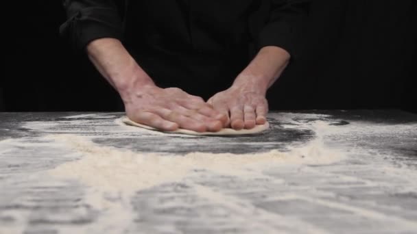 Stretching raw pizza dough with your hands. A professional chef stretches and twists soft Italian pizza dough with his hands. Slow motion. - Felvétel, videó
