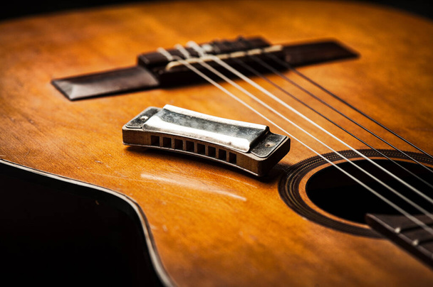 vintage ξύλινη φυσαρμόνικα ξαπλωμένη σε μια παλιά ακουστική κιθάρα. - Φωτογραφία, εικόνα