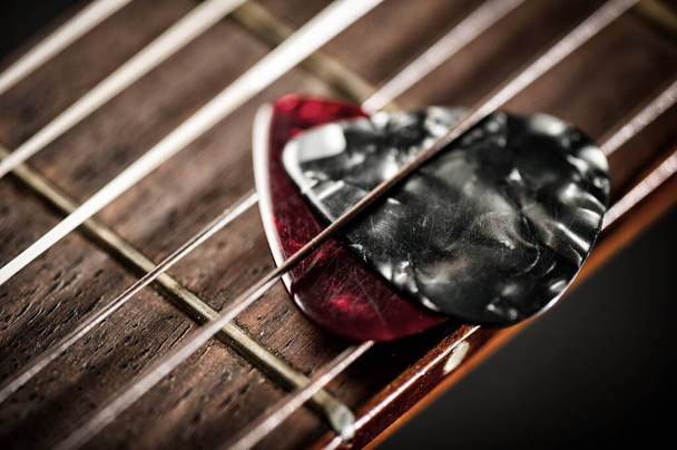 Nahaufnahme-Gitarrenpick auf einer alten klassischen Gitarre. Ein Gitarrenpick ist ein Plektrum, das für Gitarren verwendet wird. - Foto, Bild