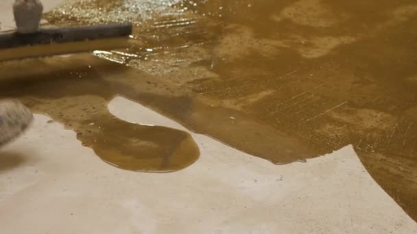 Detailní záběr na nohu pracovníka v montérkách. Vyhlazování primeru na betonové podlaze stěrkou. - Záběry, video