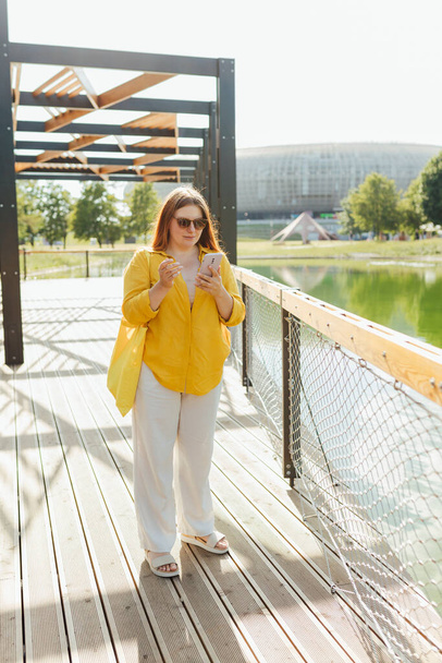 Upset young woman talking over phone disappointed hear bad news, sad pensive girl speaking having unpleasant smartphone conversation on river background. Negative emotions - 写真・画像