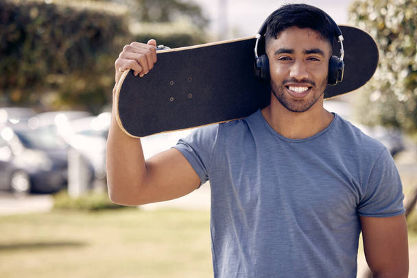 un joven que usa auriculares mientras patina afuera en la universidad. - Foto, Imagen