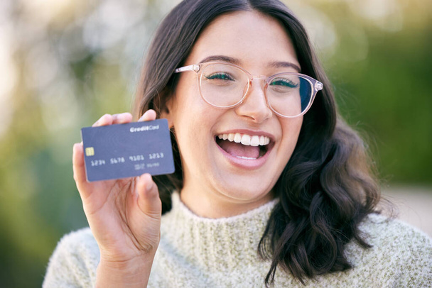 onnellinen nuori nainen, joka pitelee luottokorttia seistessään ulkona. - Valokuva, kuva