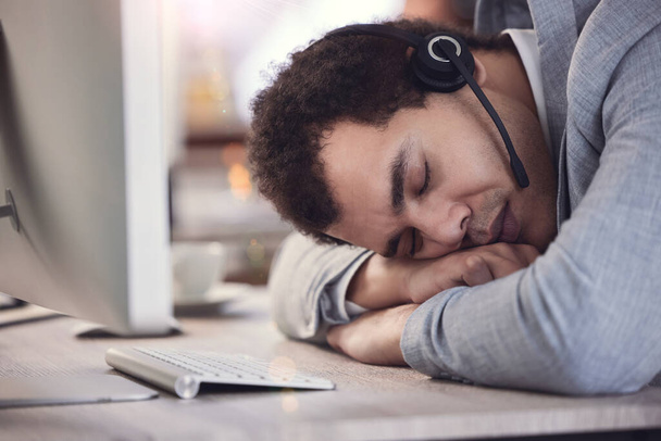 un joven agente del centro de llamadas tomando una siesta en el trabajo. - Foto, imagen