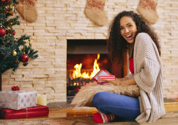 szczęśliwa młoda kobieta otwierając prezenty w Boże Narodzenie w domu. - Zdjęcie, obraz