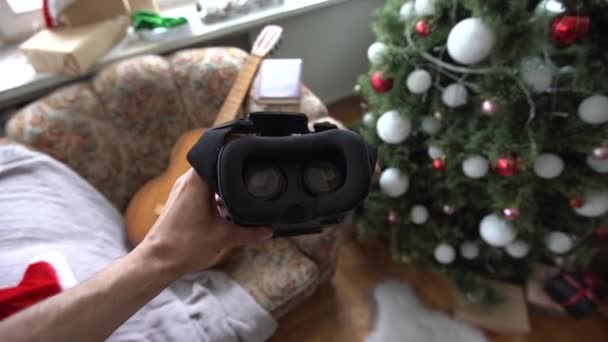 3D-Brille mit virtueller Realität in Kopfbedeckung in der Nähe des Weihnachtsbaums. - Filmmaterial, Video
