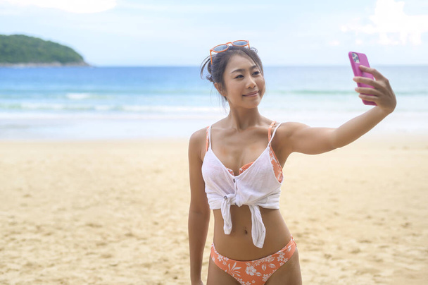 Mladá krásná žena v Bikini poslech hudby a pomocí smartphone na pláži, Léto, dovolená, dovolená, Lifestyles koncept. - Fotografie, Obrázek