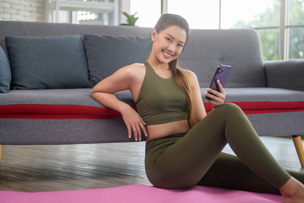 Young fitness woman in sportswear using smart phone while exercising at home, Healthy and Lifestyles. - Φωτογραφία, εικόνα
