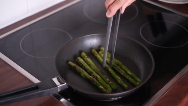 l'uomo frigge asparagi su una padella di teflon. corretta alimentazione vegetarianismo - Filmati, video