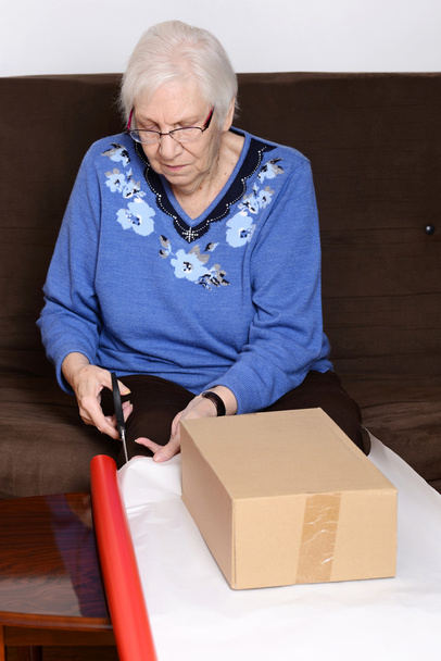 Старшая женщина режет рождественскую бумагу
 - Фото, изображение
