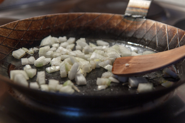 Cebollas en sartén de hierro con espátula
 - Foto, imagen