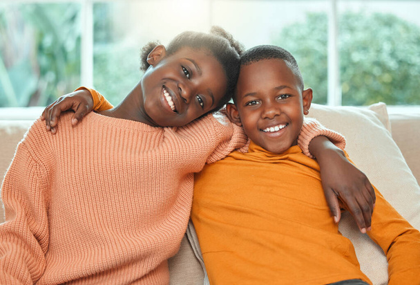 Portrait of a brother and sister relaxing together on a sofa at home. - Photo, image