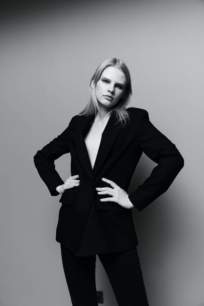 The middle portrait with the legs of a professional model in a classic suit posing with both hands on the waist m looks into the camera. High quality photo - Photo, Image
