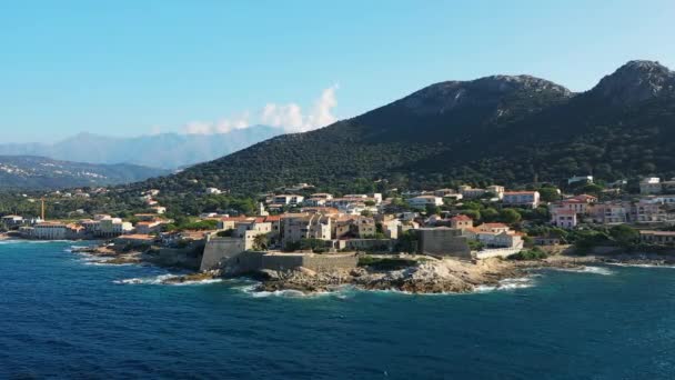 De stad Calvi en zijn middeleeuwse fort aan de voet van de bergen, in Europa, in Frankrijk, op Corsica, aan de Middellandse Zee, in de zomer, op een zonnige dag. - Video