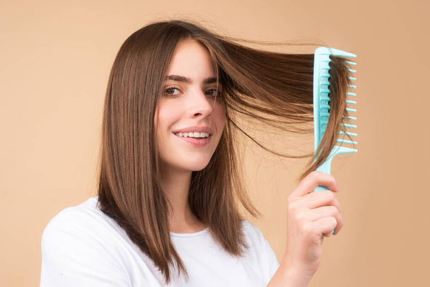 Attractive woman combing hair. Beautiful girl combs hair. Haircare concept - Zdjęcie, obraz