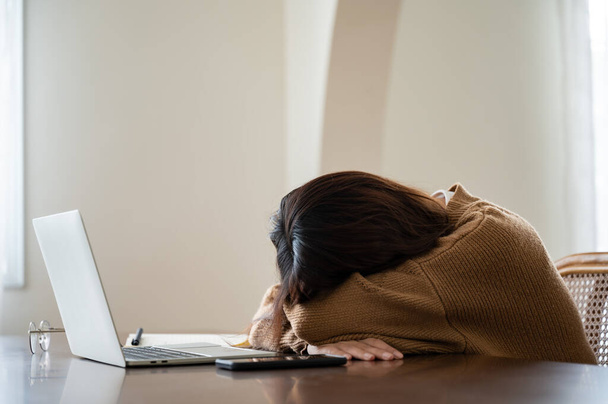 Asian woman lying face down on the table. Overworked tired young asian woman, having eyesight problem after computer laptop wor - Foto, Imagem