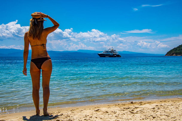 Beautiful, brunette young girl with raised hands, looking towards the ocean in Skiathos island, Greece - Φωτογραφία, εικόνα