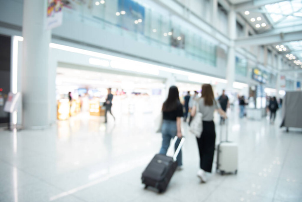 Fondo borroso de personas, pasajeros con equipaje caminando y mirando alrededor tienda libre de impuestos en el aeropuerto - Foto, imagen