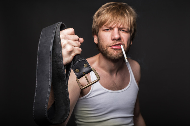 Angry man threatens with belt. Concept: Violence in the family. Abuse - Foto, imagen