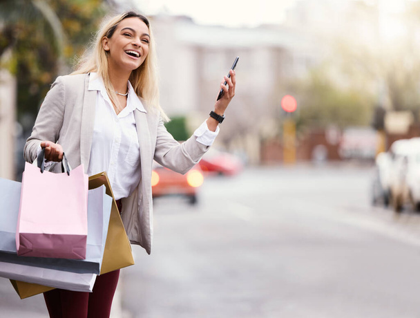 una atractiva joven revisando su celular para ver dónde está su taxi mientras va de compras por la ciudad. - Foto, imagen