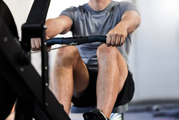 un atlético irreconocible haciendo ejercicio en una máquina de remo en el gimnasio. - Foto, imagen