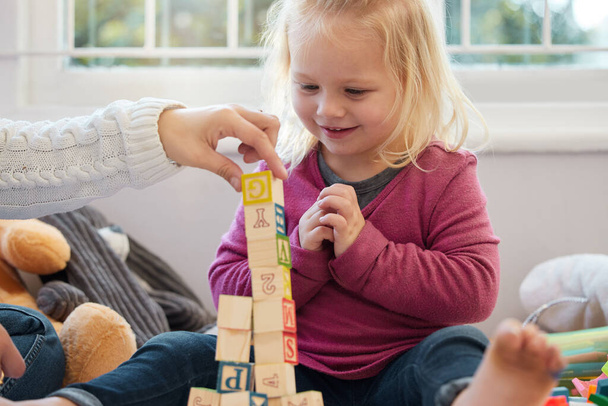 a little girl stacking blocks with her mother at home. - Valokuva, kuva