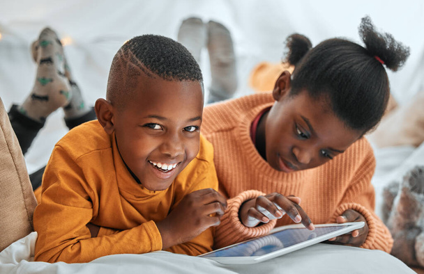 Retrato de un niño usando una tableta digital con su hermana en casa. - Foto, imagen