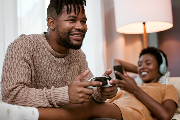 a handsome young man playing video games while relaxing on the sofa at home with his wife. - Fotoğraf, Görsel