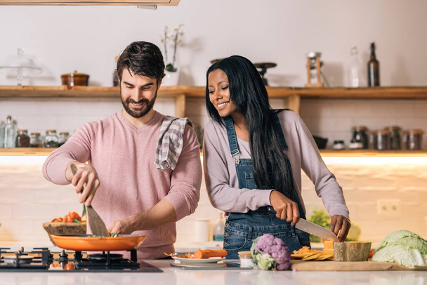 Cute multi-ethnic couple preparing lunch together in the kitchen at home. - Fotoğraf, Görsel