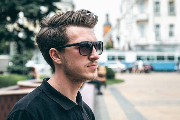 Portrait of a young man in sunglasses in the city in summer, copy space. - Photo, Image