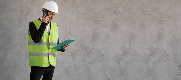 Builder manager. Male engineer speaks on phone. Construction paper plans from architect. Man in builder's uniform isolated on background. Architect calls client. Construction company employee. Banner - Photo, Image
