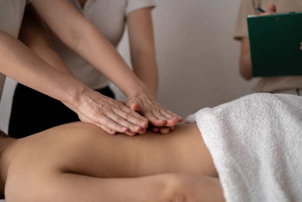 Massage courses, training of massage therapists, teacher helps student to do wellness back massage - Foto, Imagem