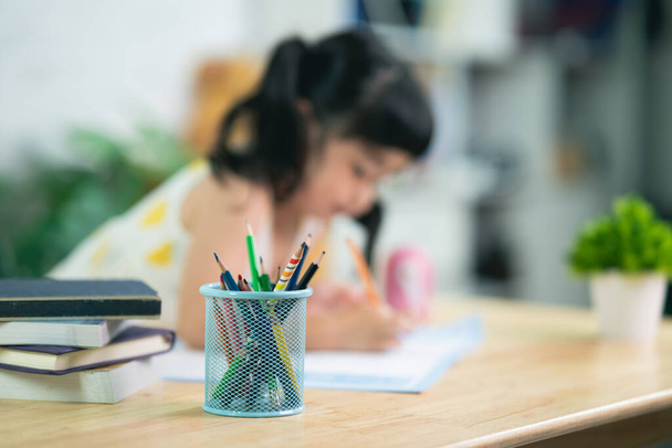 close up pencil holder and cute little child wearing white headphone painting with colorful paints. Asian girl using wood color drawing color.Baby artist activity lifestyle concept. - 写真・画像