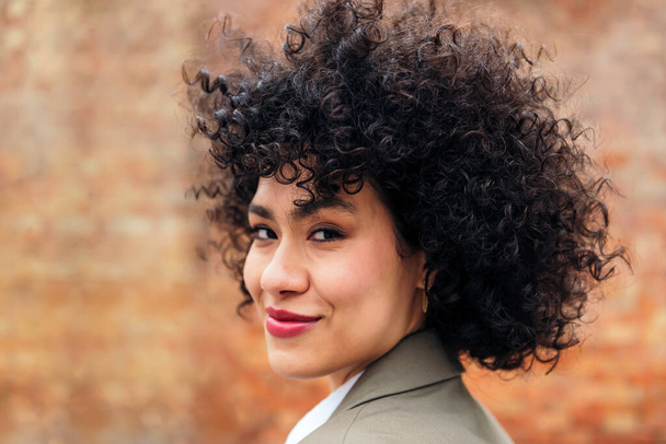 portrait of a young latin woman with curly hair smiling looking at the camera, concept of youth and happiness, copy space for text - Photo, Image